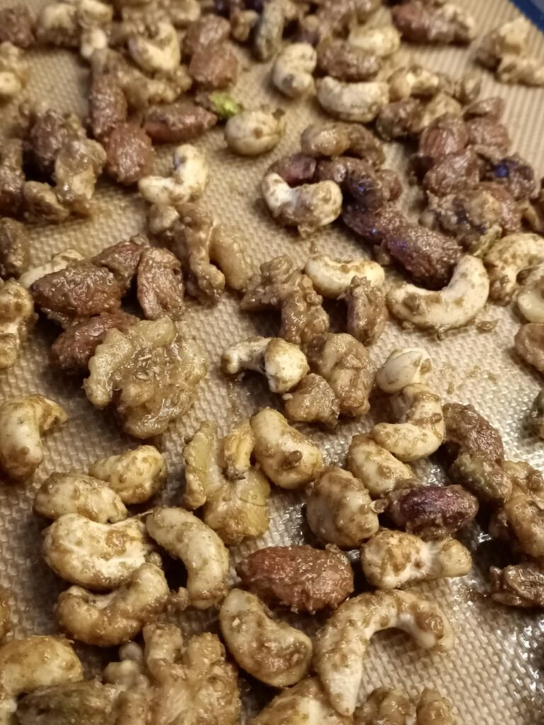 uncooked nuts covered in spices on a baking tray and silicone mat