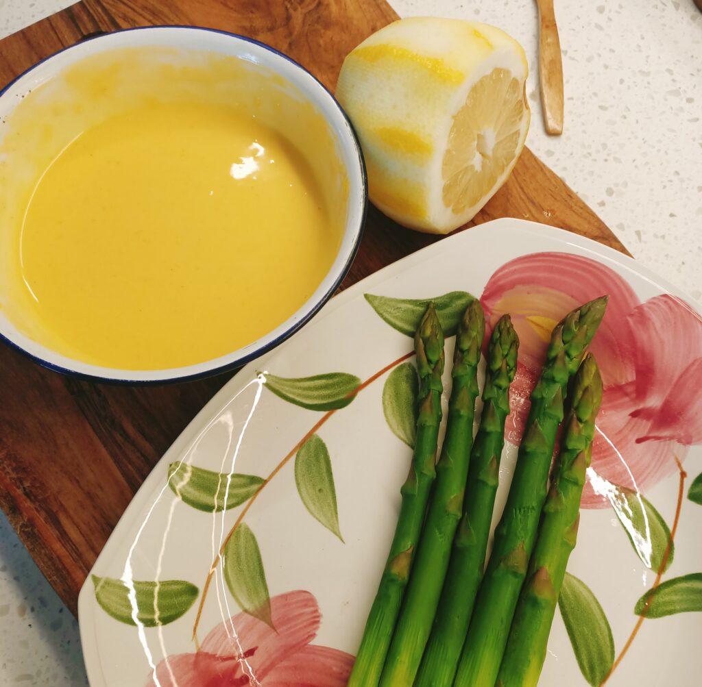 photo of a bowl of mayonnaise, hlaf a lemon and some aspragus