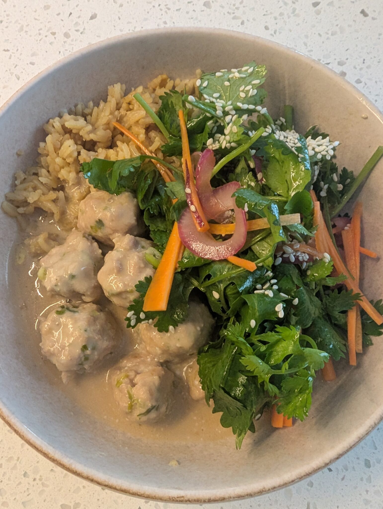 a bowl of beige meatballs and a colourful salad