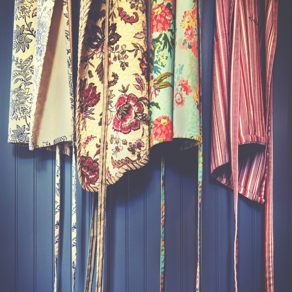 colourful aprons hung up against a dark blue wall
