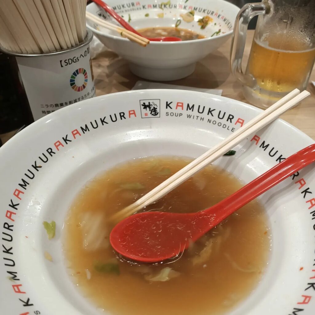 photo of two bowls with a red spoon and chopsticks and some noodles and broth
