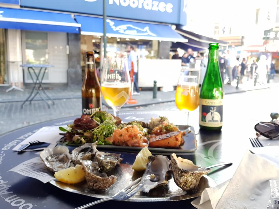 photo of a plate of seafood with some beers in the background