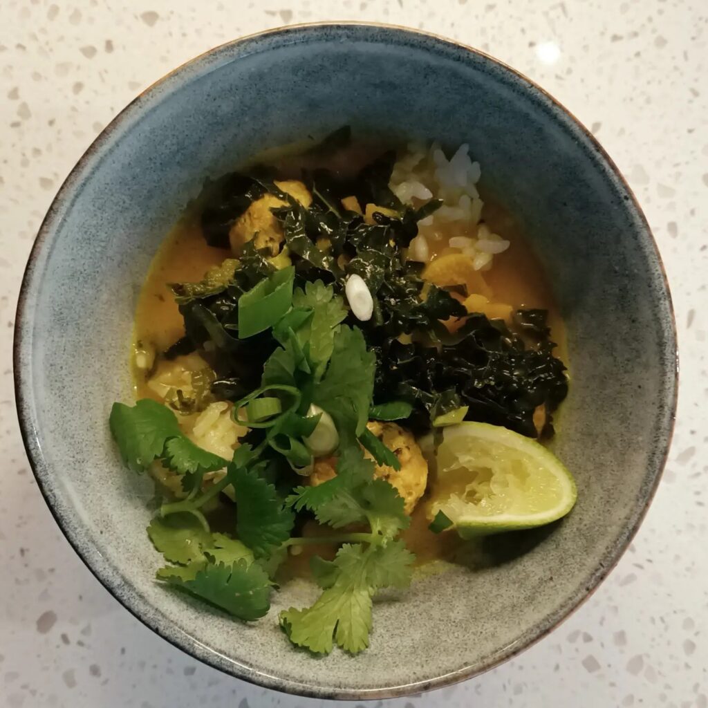 photo of a bowl with rice broth and topped with green herbs