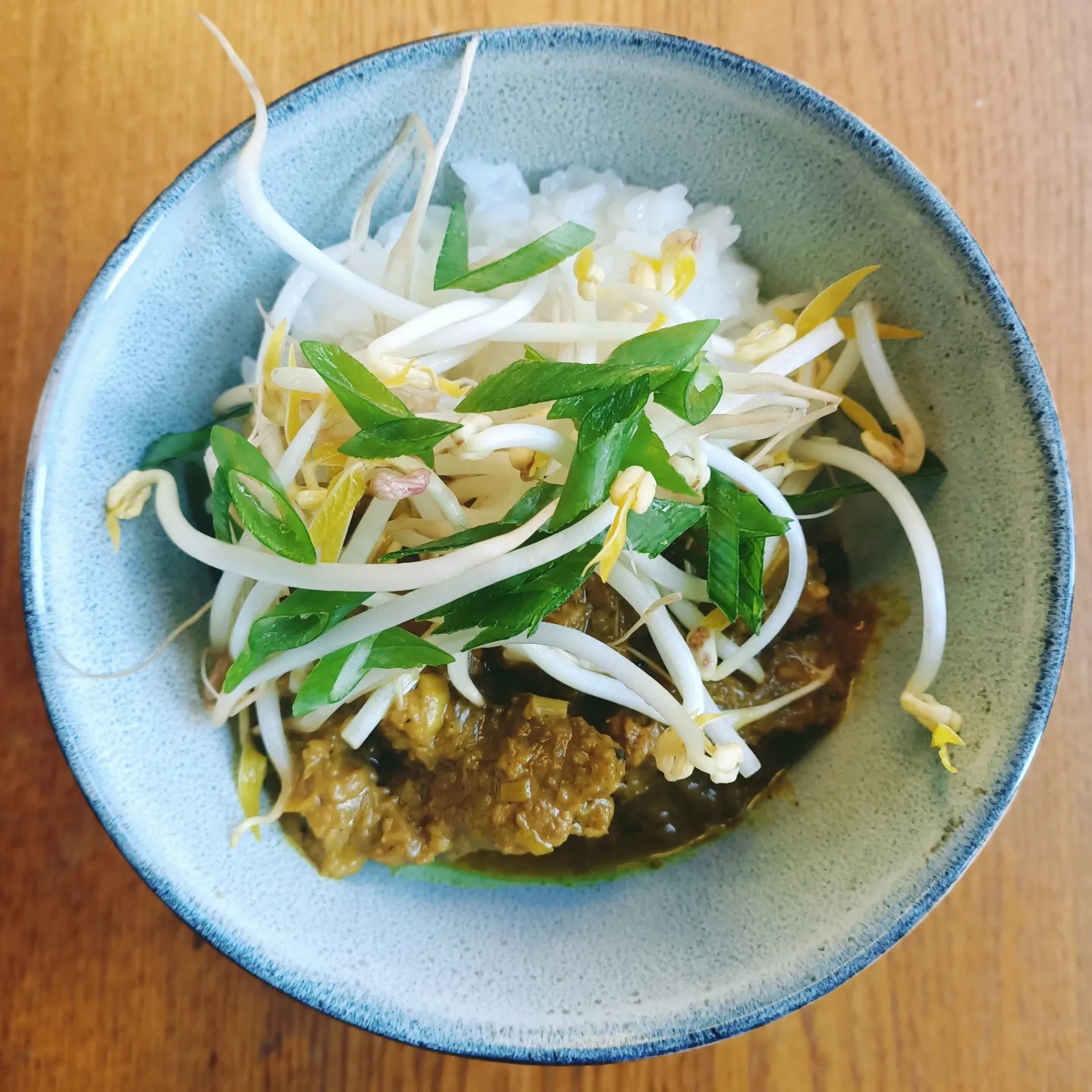 a pale blue bowl that has some rice, vegetables and a curry