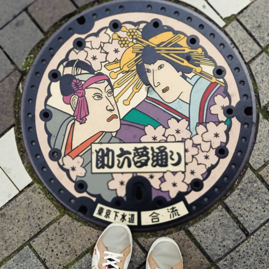 photo of a street drain lid in Japan with two cartoon figures