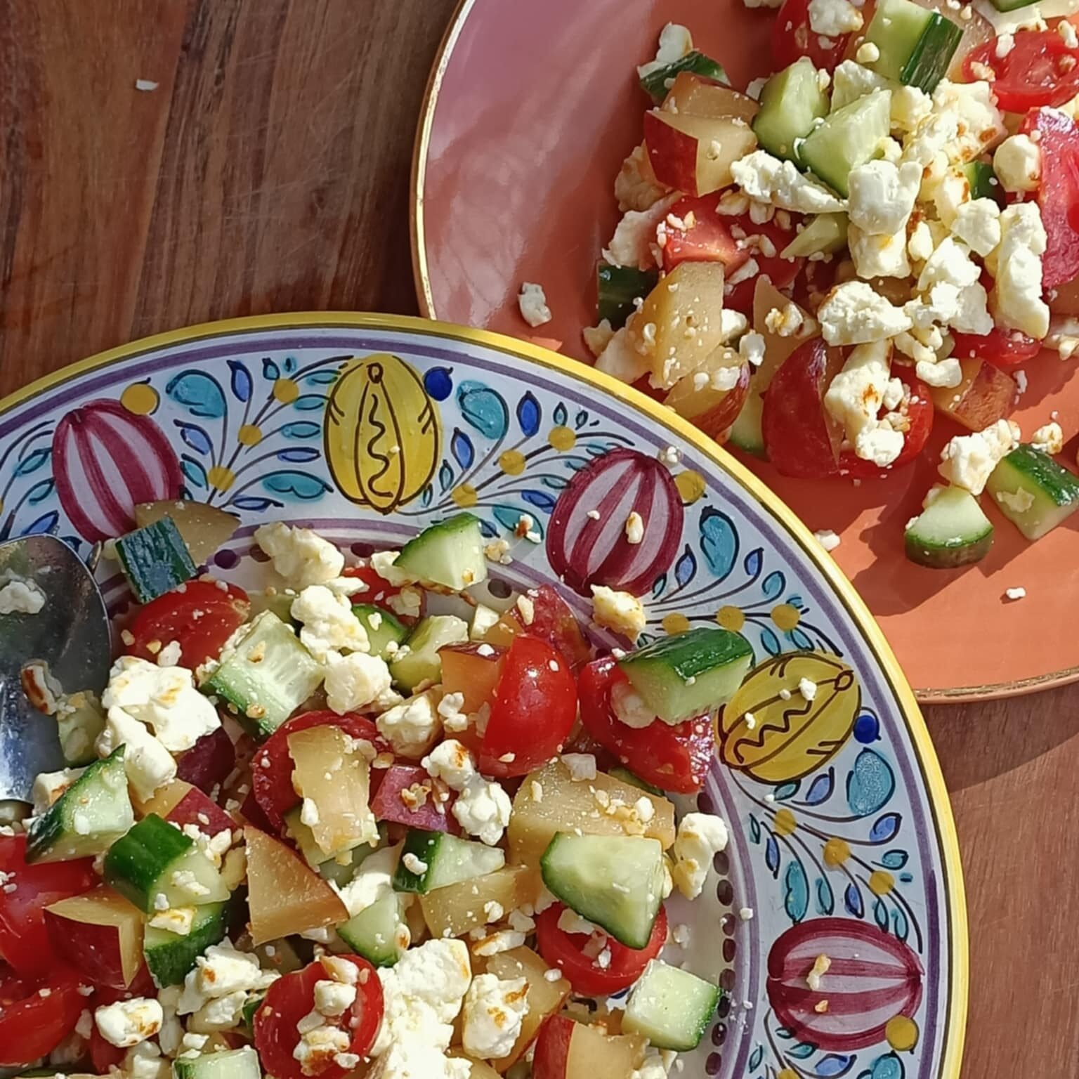 colourful plates with a colourful salad with tomato, fruit and cucumber with cheese