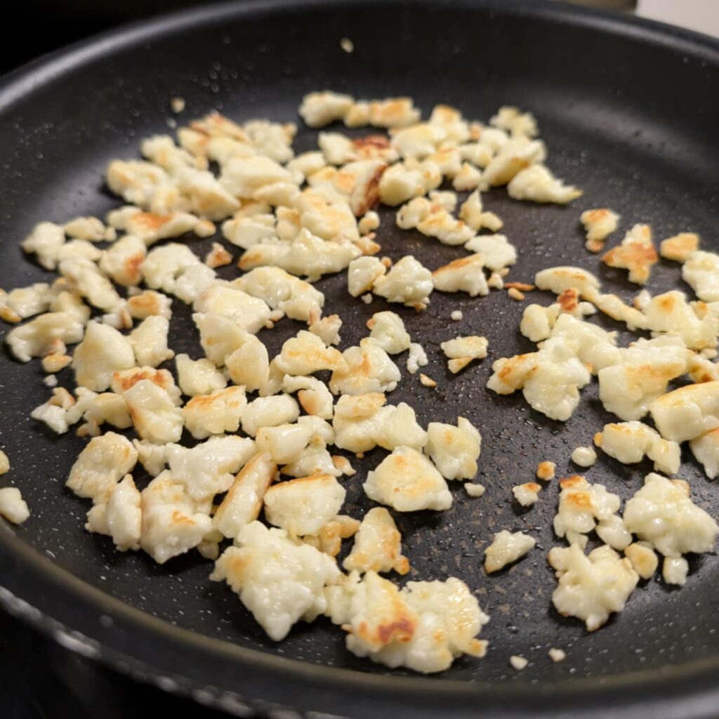 a black fry pan with crumbled cooked cheese