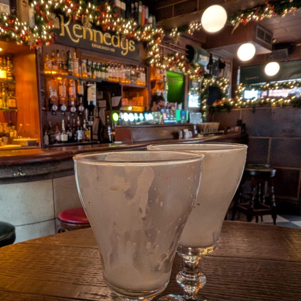photo of two empty glasses in front of bar with christmas lights