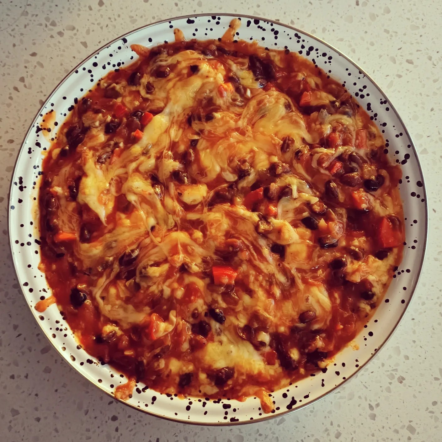 photo of a bowl with cheese and tomatoes and beans swirled together