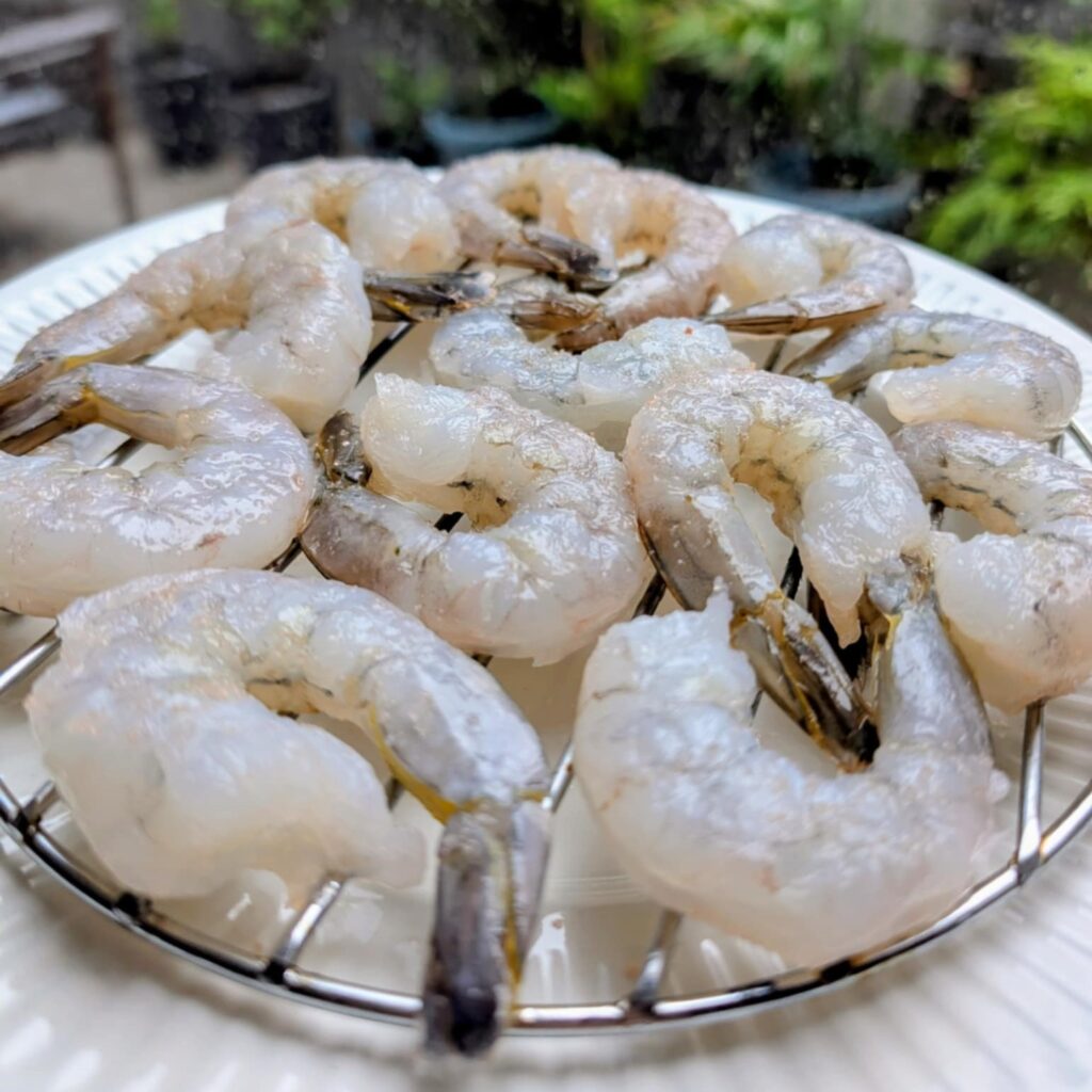 photo of raw prawns on a metal rack in front of a window