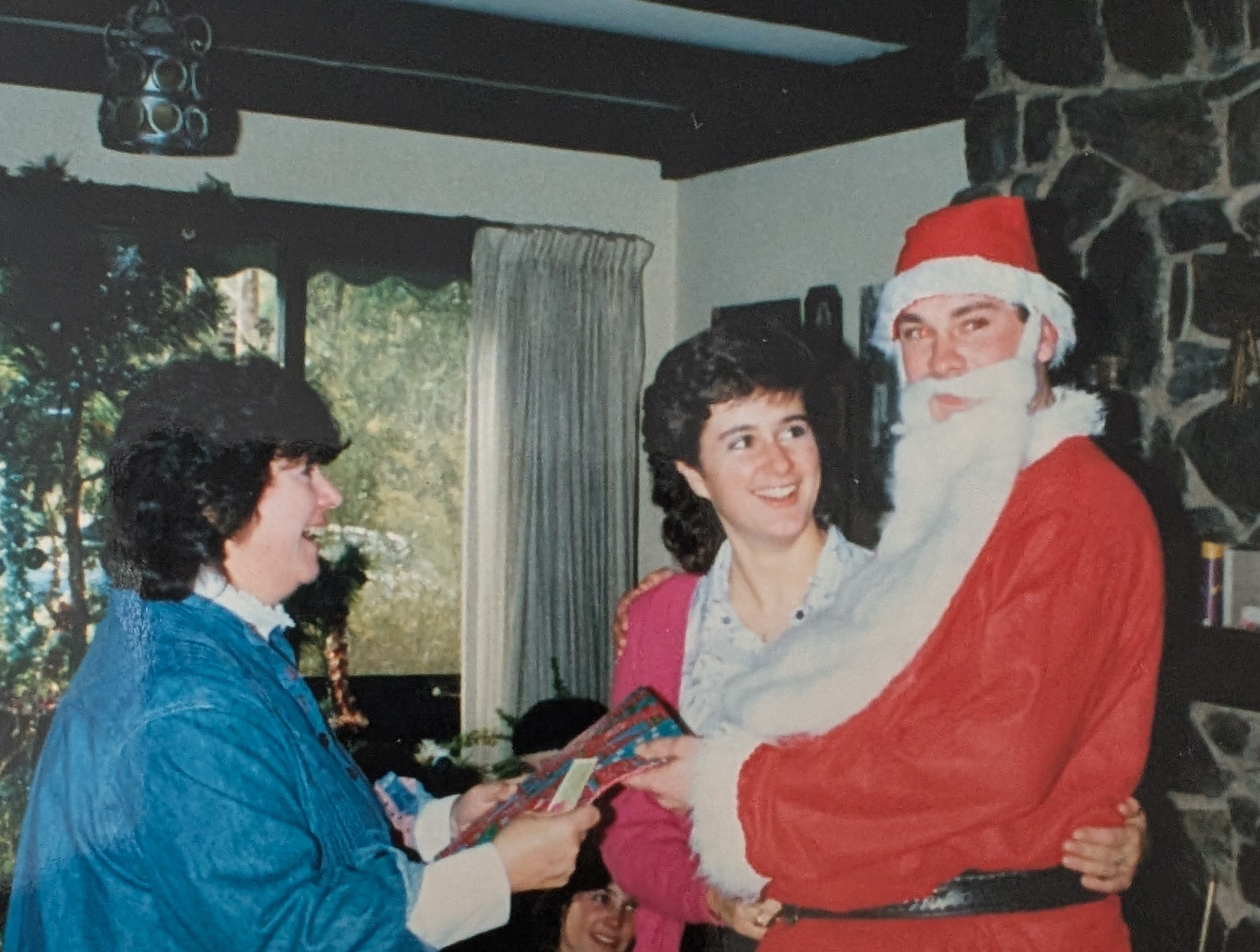 photo from 1980s with two women with dark hair and a man dressed as Santa Claus