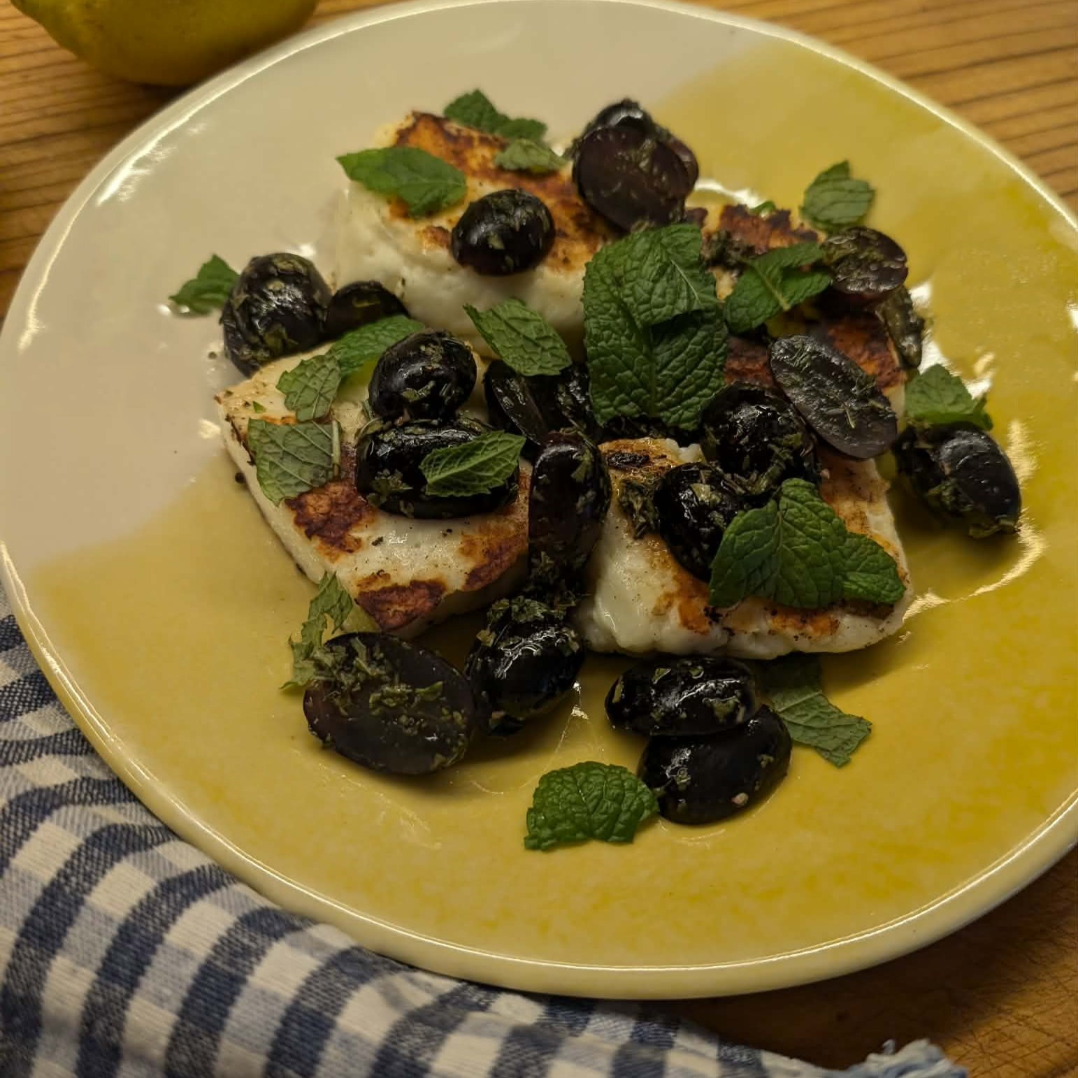 phoo of black grapes, mint herb and grilled cheese on a yellow plate